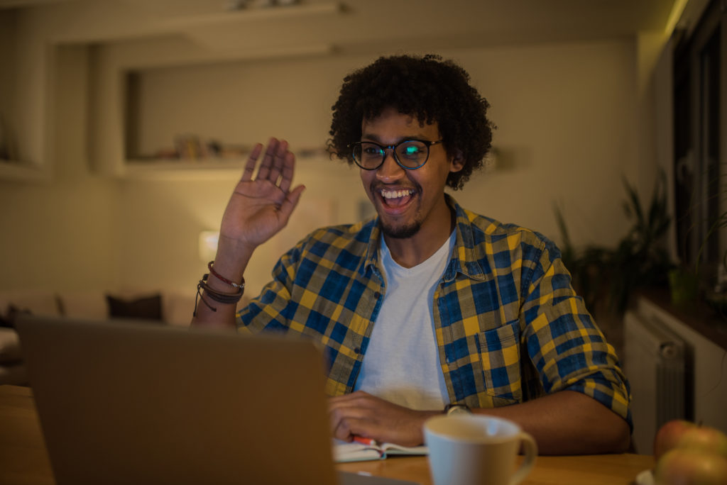 Young happy man using laptop and waving his hand