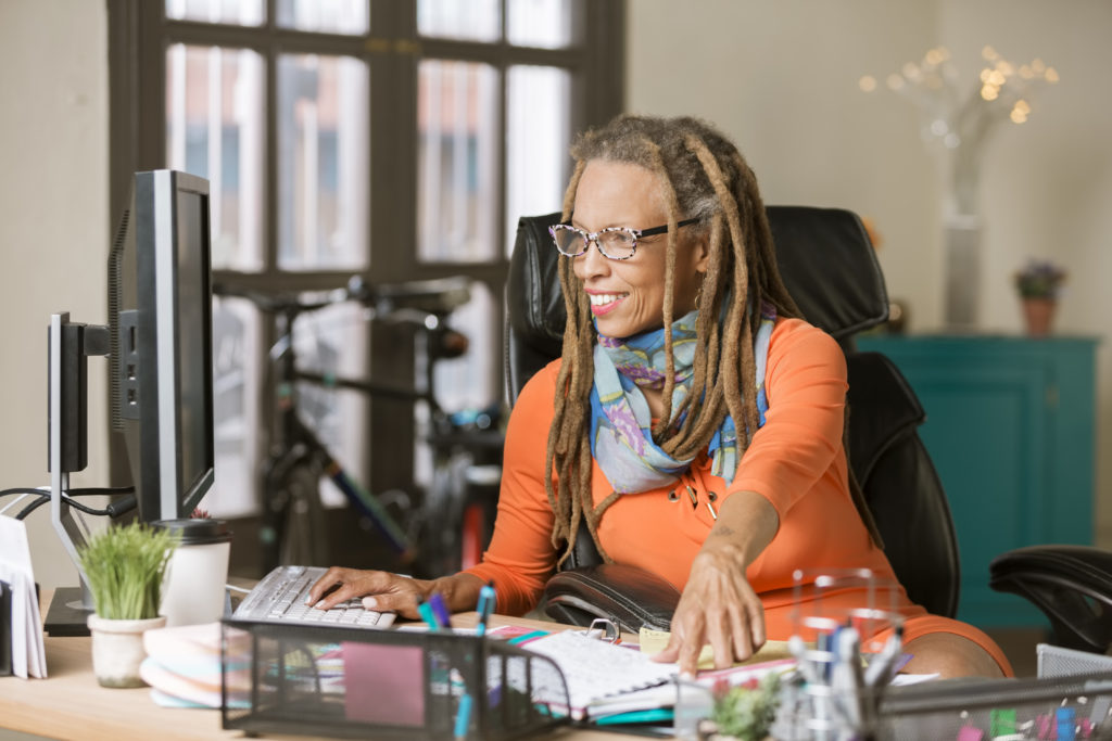 Confident professional with dreadlocks working on her computer