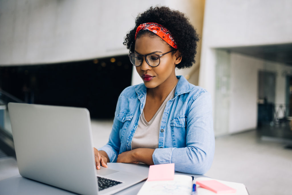Young African female hard at work on a laptop while sitting at a table