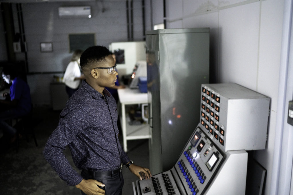 Young male employee working and using industrial machine