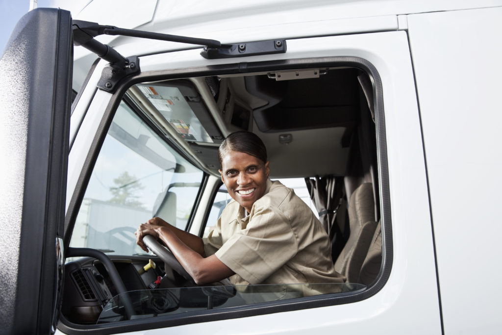 Female African American truck driver (50s) sitting in cab of semi-truck