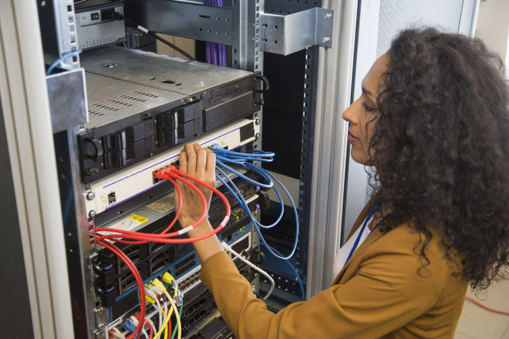 Female computer technician connecting cable in server room