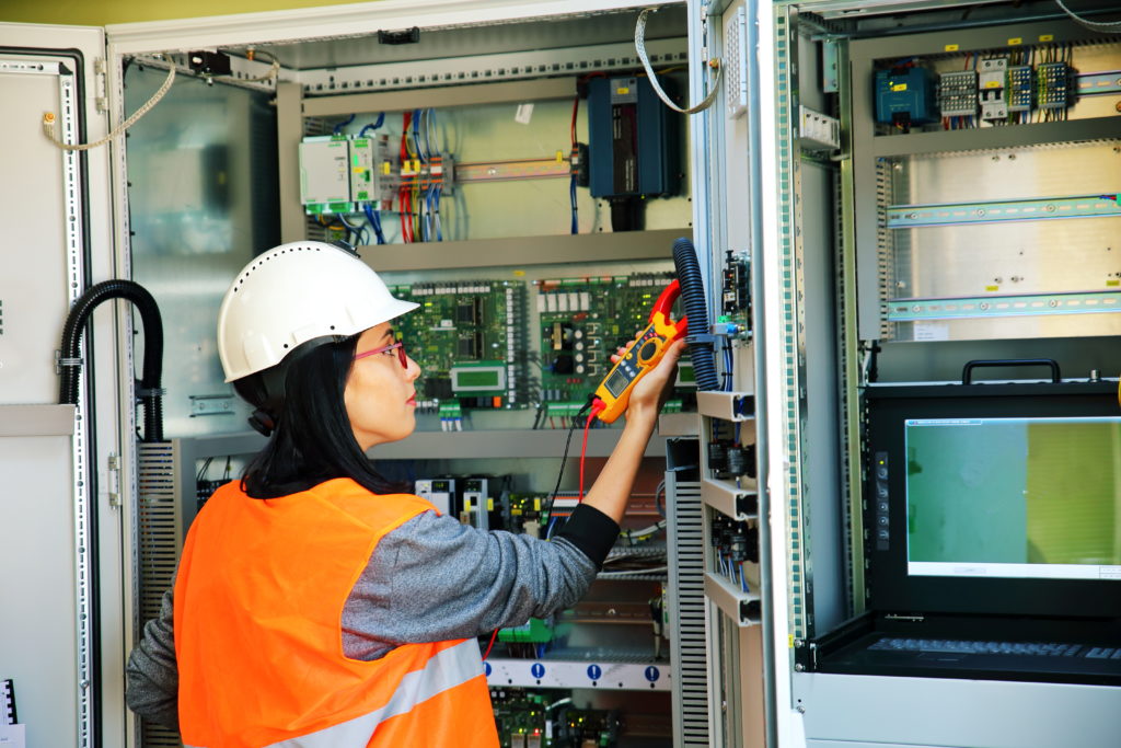 Young female maintenance engineer testing voltage